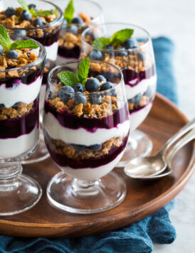 Yogurt Parfaits layered with plain Greek yogurt, blueberry sauce and granola.