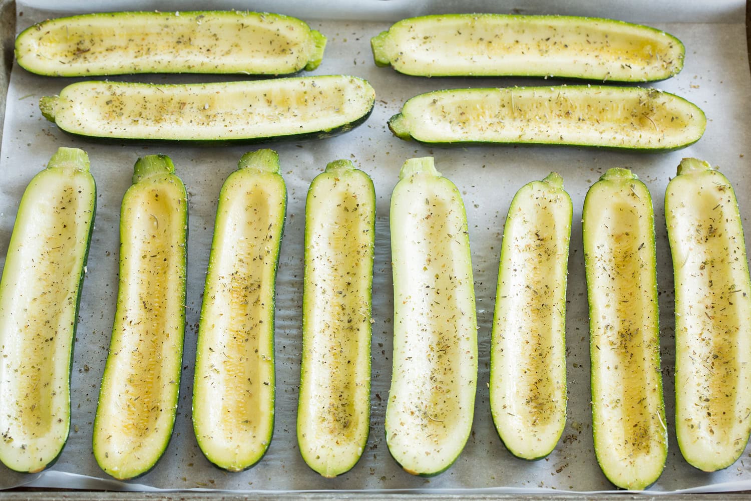 Zucchini boat halves on a baking sheet.